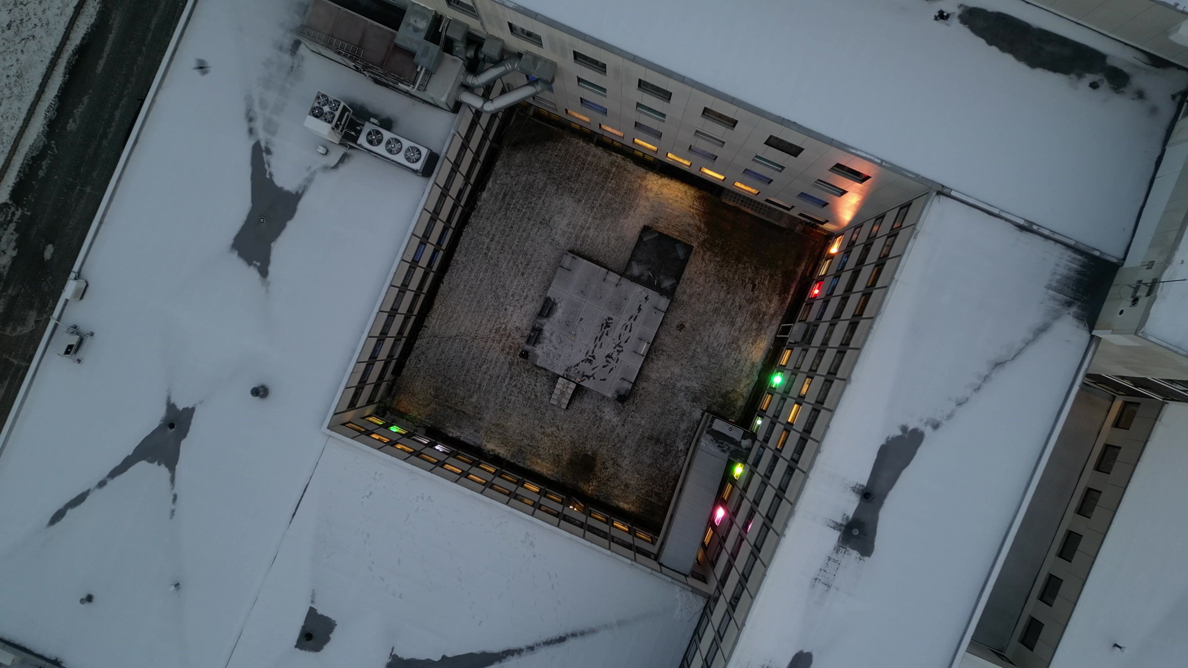 An aerial view of the old hospital at Prestøya in snow, a string of lights along its roof