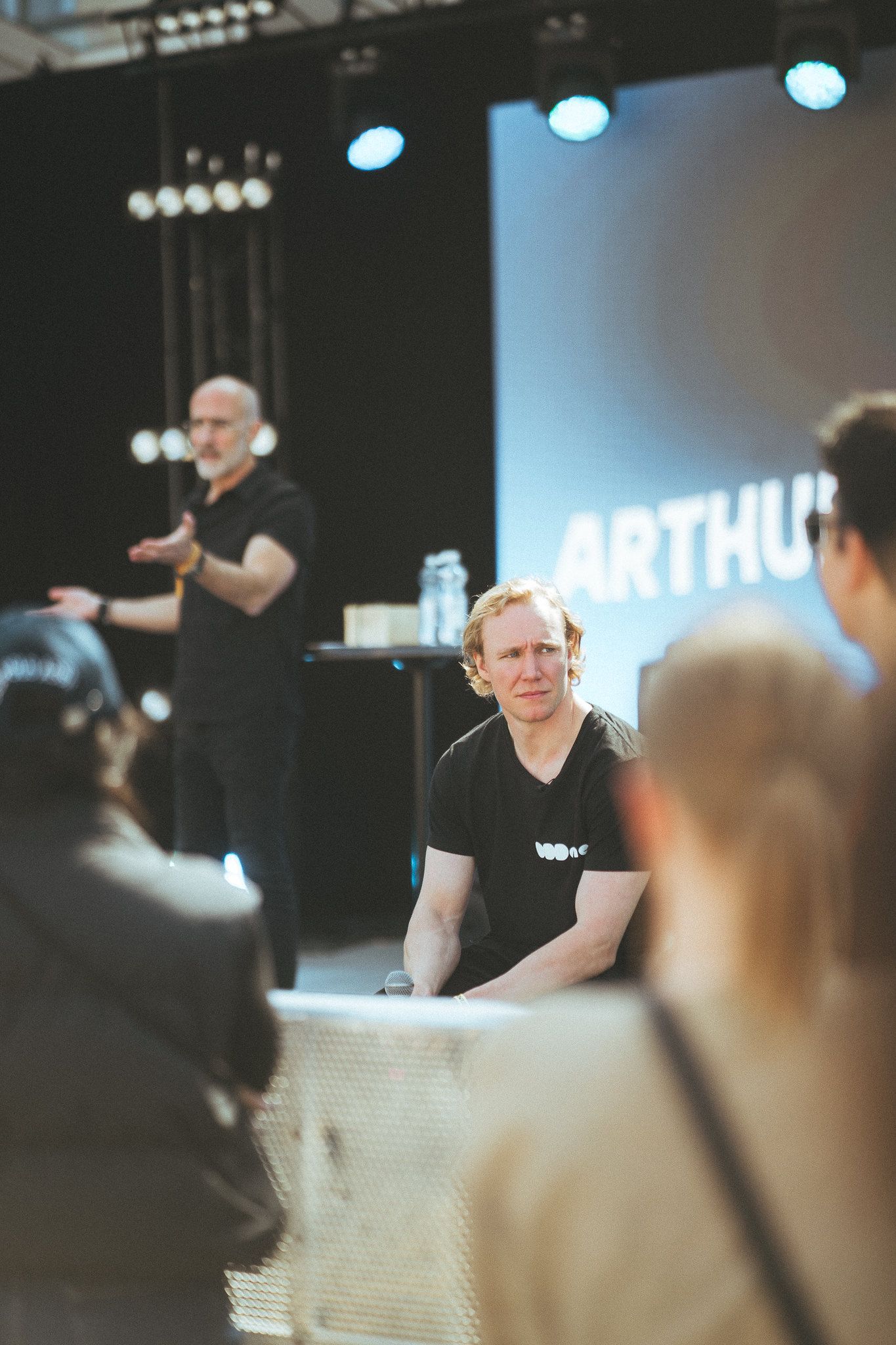 Ronny Eriksson at the edge of the stage, a speaker talking behind him