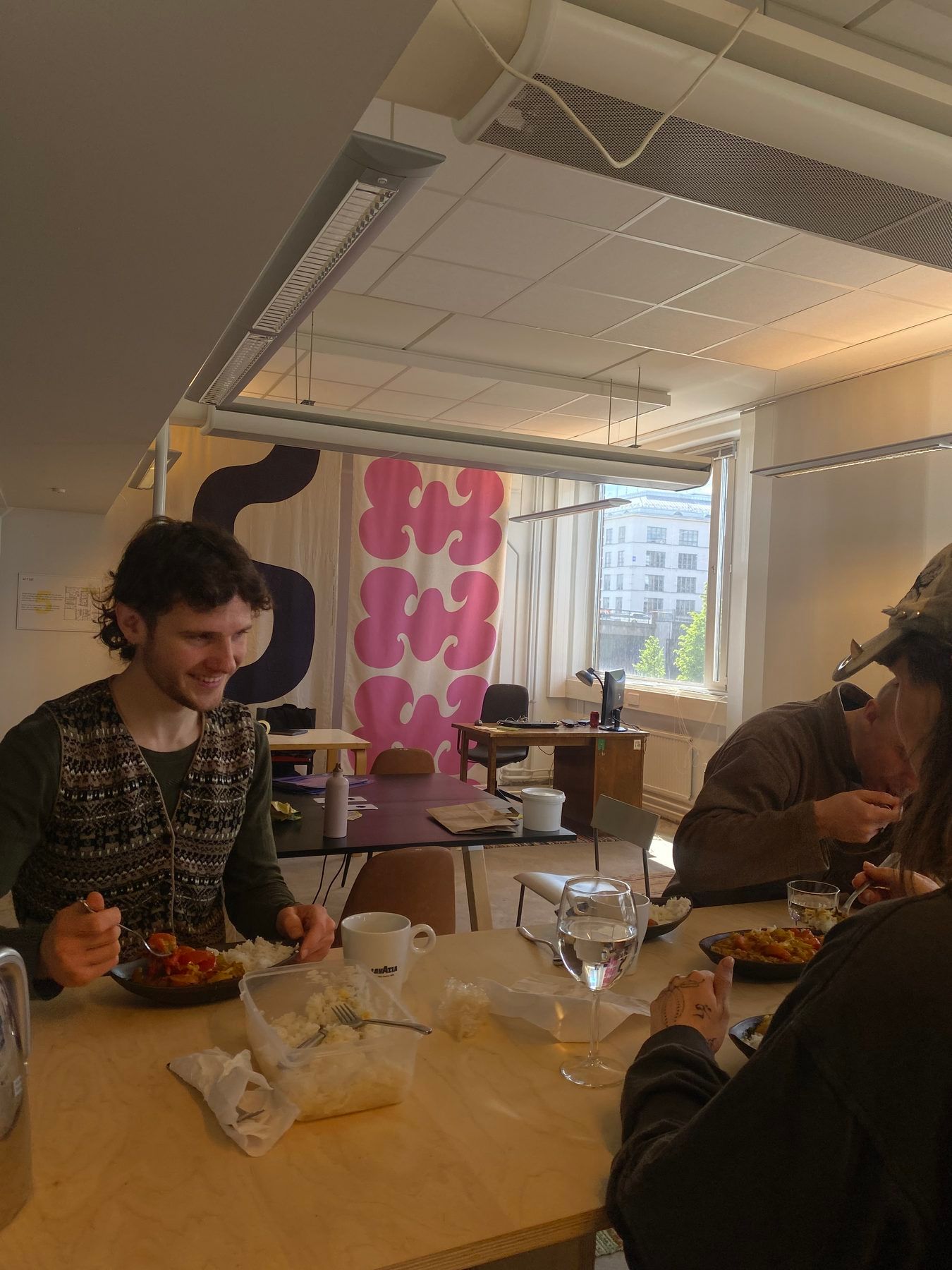 People having lunch together around a table in the ODDspace workspace, a window behind them