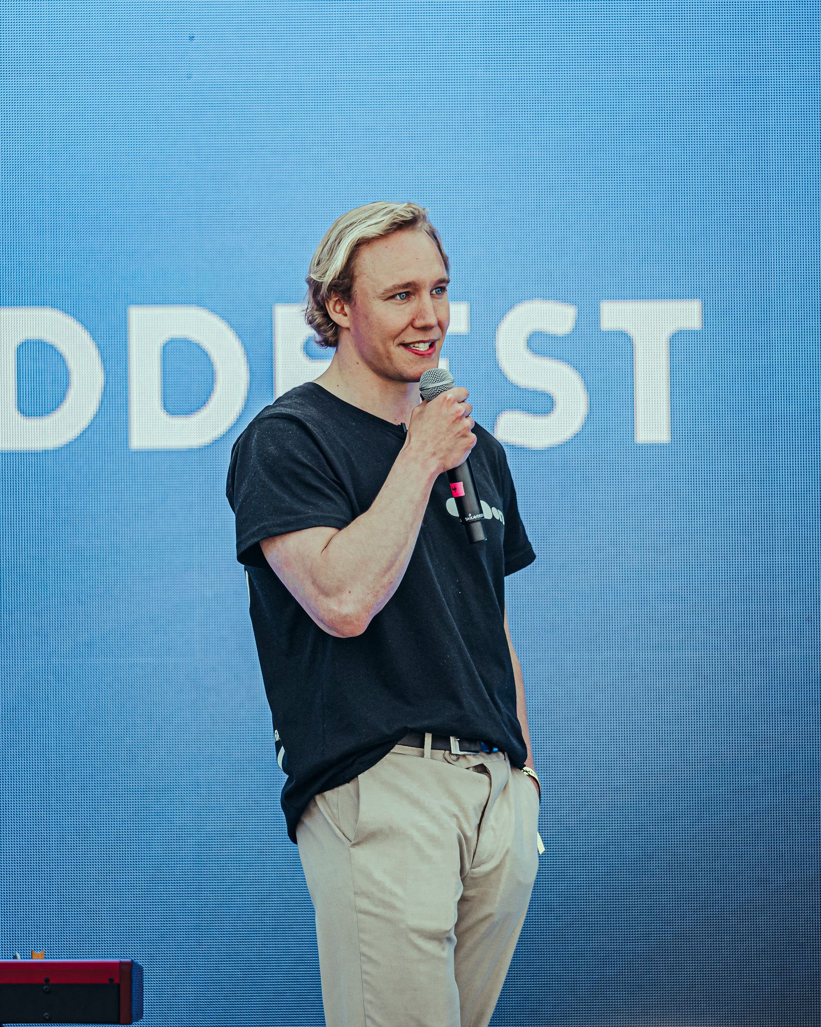 Ronny Eriksson with a handheld microphone in front of an ODDfest screen