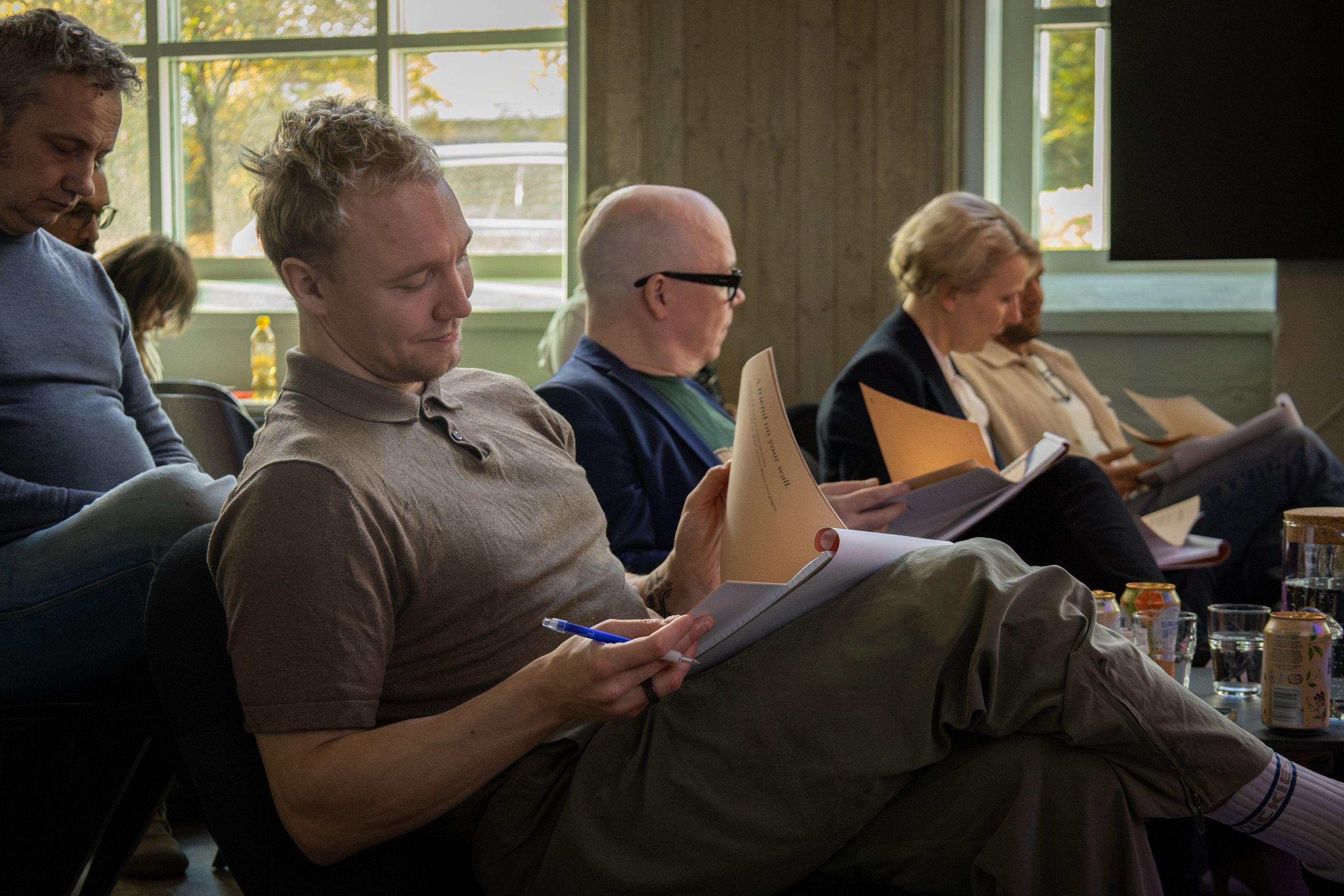 Ronny Eriksson reading a pitch sheet, pen in hand, the jury beside him leafing through theirs