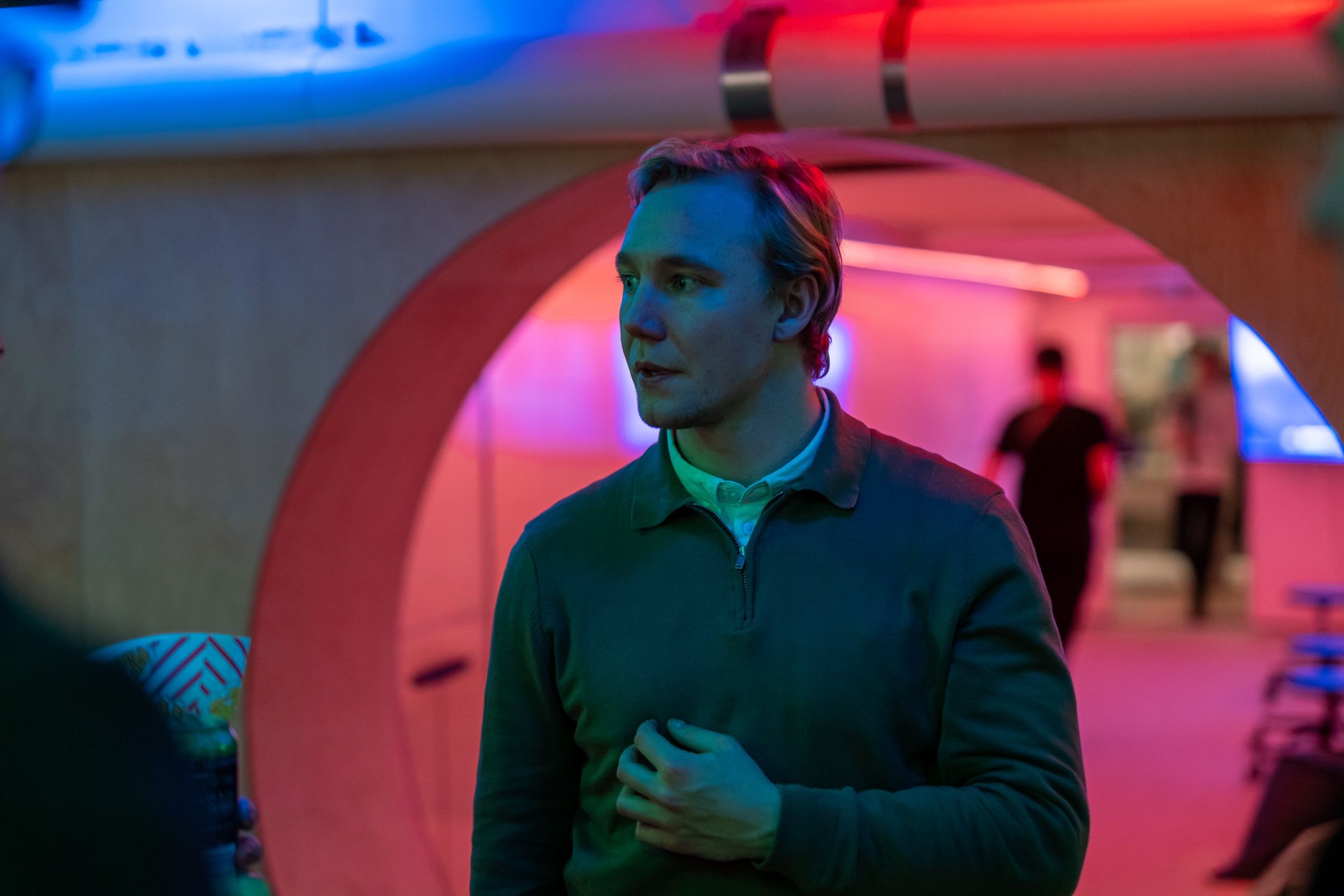 Ronny Eriksson in a green jumper under a red neon arch at night