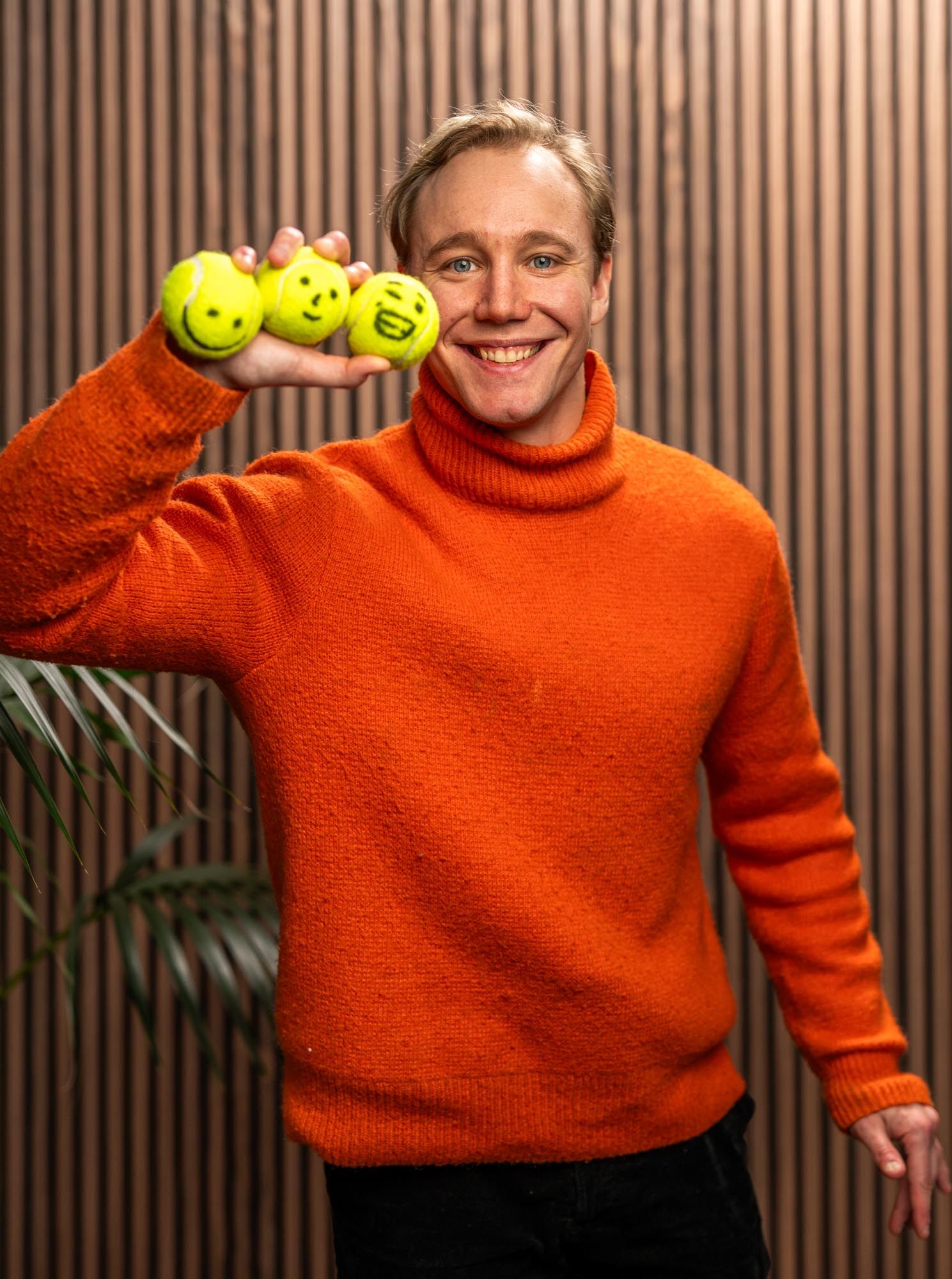 Ronny Eriksson in an orange roll-⁠neck holding three yellow smiley balls