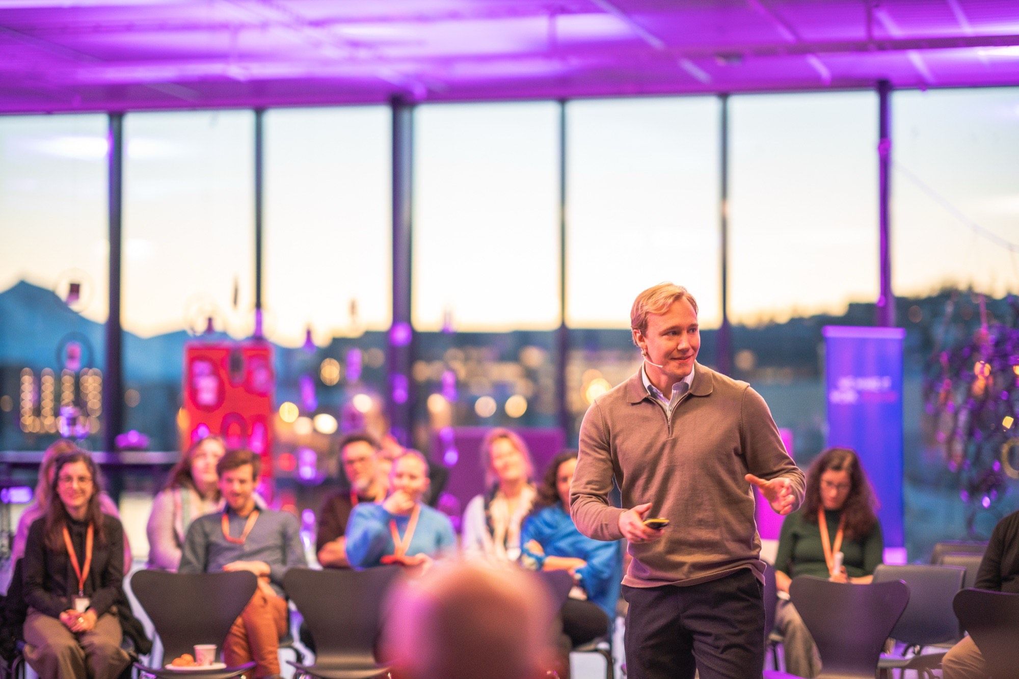 Ronny Eriksson hosting a conversation in a glass-⁠walled room at sunset, guests seated in a half circle