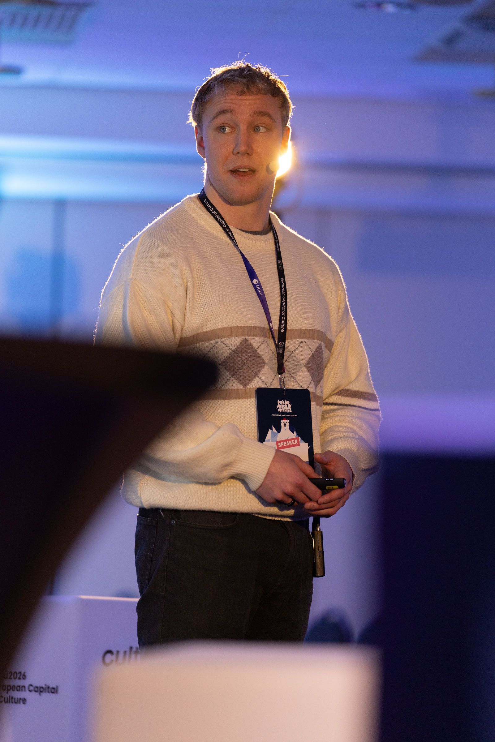Ronny Eriksson on stage with a clicker, full figure, purple light