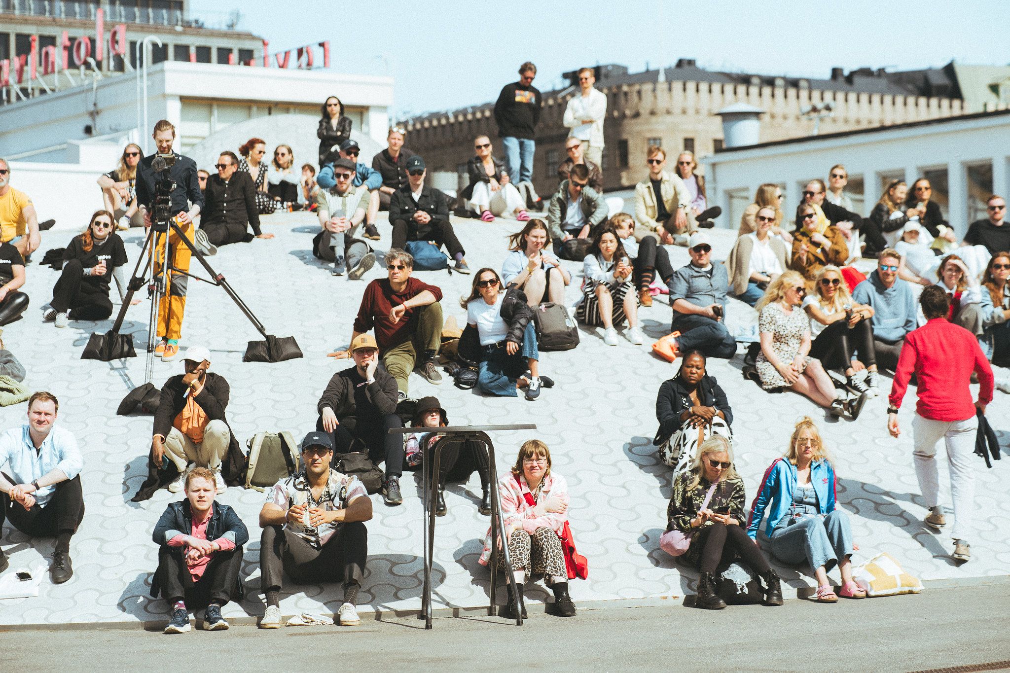 A crowd sitting on the stone domes of Amos Rex in daylight